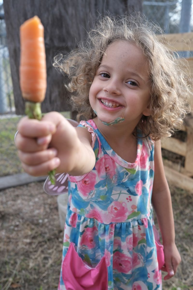 Blanton student proudly holding a carrot grown in the school garden